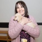 A member of staff cuddling a puppy. Puppy yoga is good for the pups too!