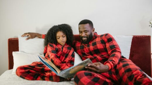 Father and daughter in pyjamas reading a book