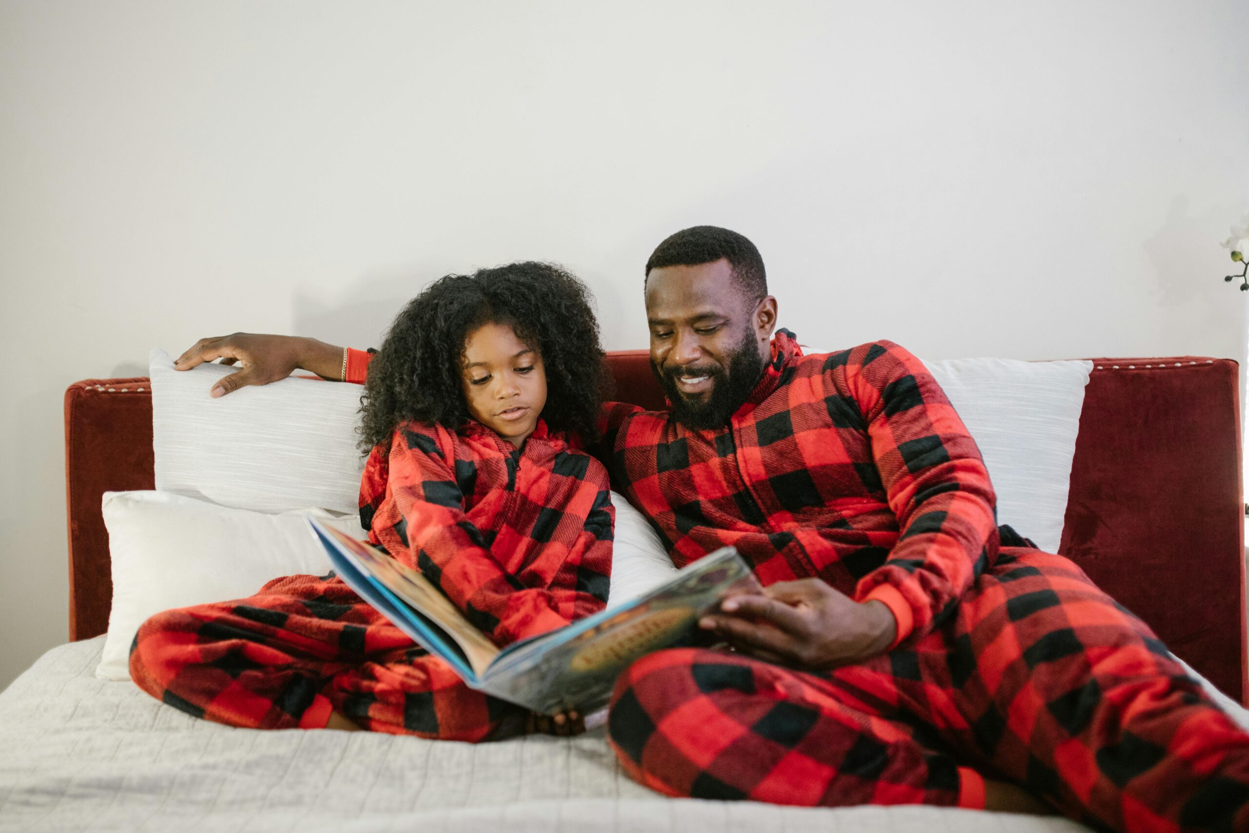 Father and daughter in pyjamas reading a book
