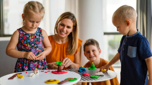 Childcare in action: Children playing with plasticine as carer helps