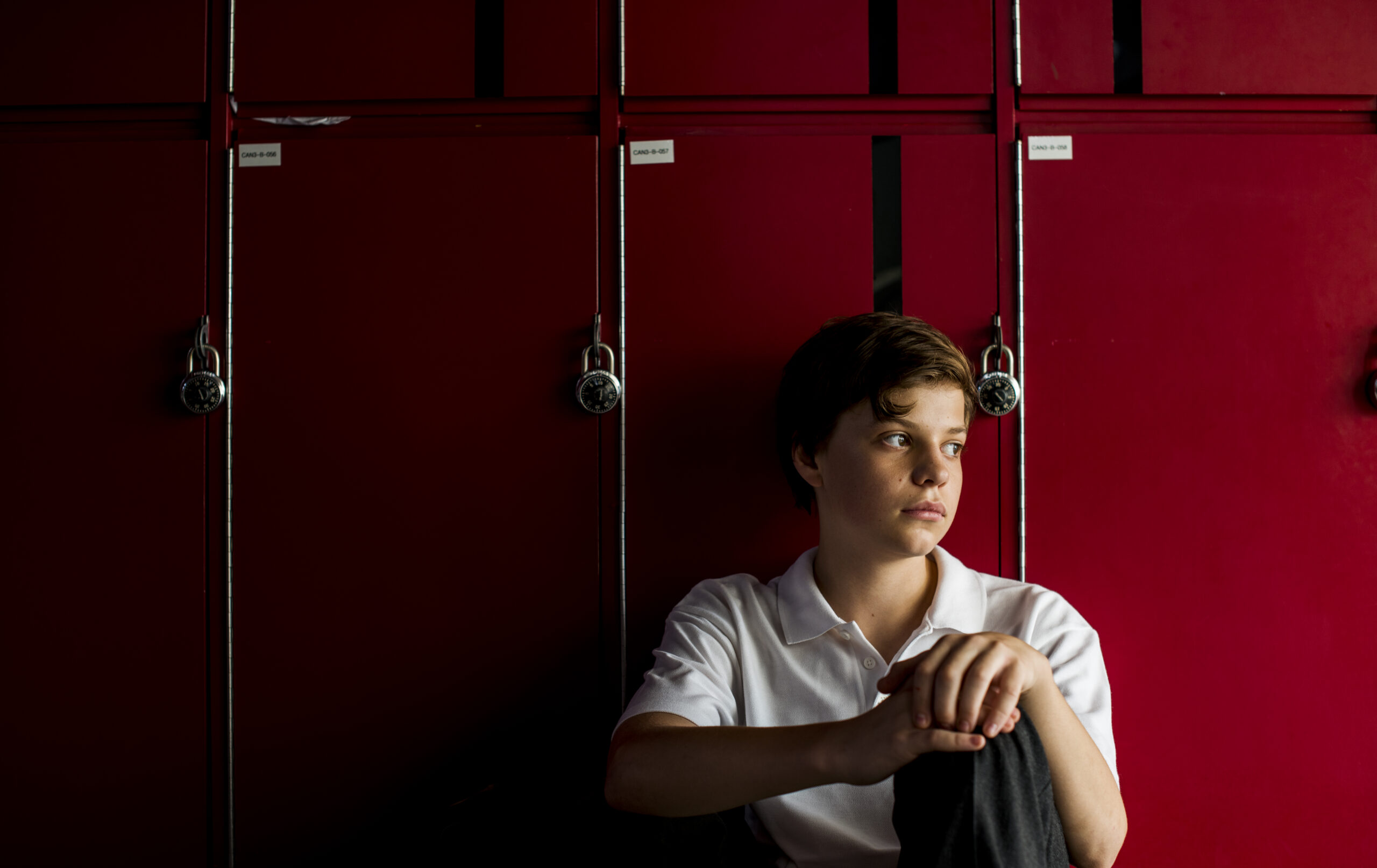 Student sitting in-front of lockers sadly